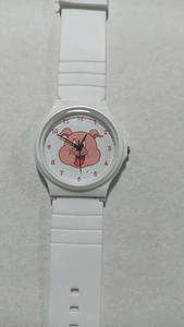 Close-up of white quartz exam watch with pink cartoon pig dial and silicone strap