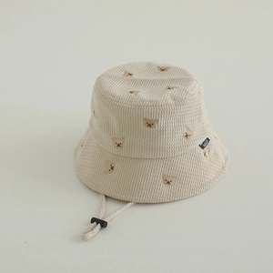 Detail eines beigen Cord-Fischerhuts mit Bärenstickerei und verstellbarem Windseil
