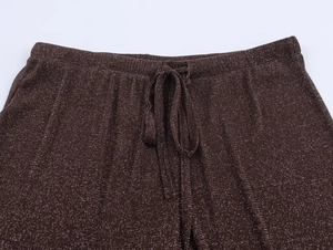 Detail view of metallic knit trousers with an elastic waistband and drawstring ties