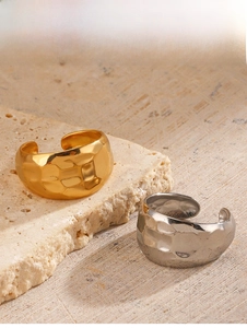 Detailed view of hammered 18K gold and silver open rings on stone texture background