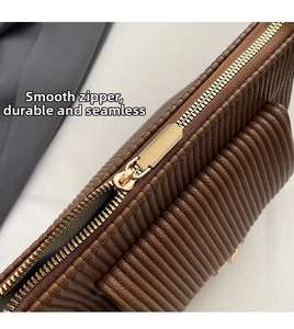 Detail of smooth gold zipper and brown pleated leather texture on the stylish bag
