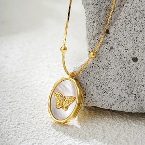 Golden butterfly necklace with mother of pearl shell pendant on grey stone display