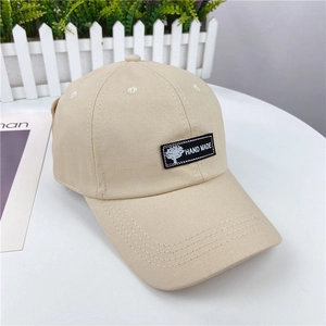Detailed close-up of beige cotton baseball cap with hand made tree patch and curved brim