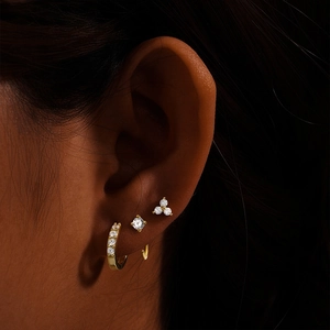 Close-up of gold turquoise earring set including huggie and studs on model's ear