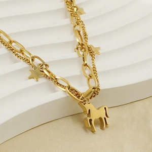 Détail d'un bracelet double couche doré avec breloques étoile et cheval sur support blanc