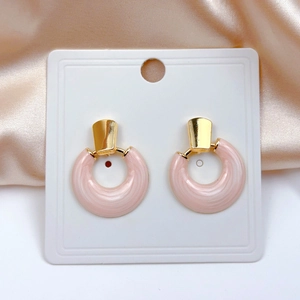 Detailed close-up of pink marble pattern round earrings on elegant champagne silk fabric