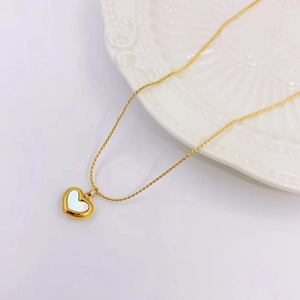 Close-up of heart-shaped gold necklace with iridescent white mother-of-pearl inlay