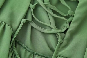 Detail of green V-neck dress featuring cross drawstring lace-up and pleated chiffon fabric