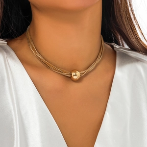 Detail of layered gold snake chains with a large polished ball pendant on a model