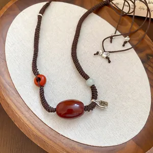 Vintage wax rope necklace with red agate beads and silver pendant on linen background