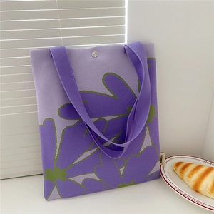 Detail of purple knitted tote bag with green flower pattern and silver snap closure