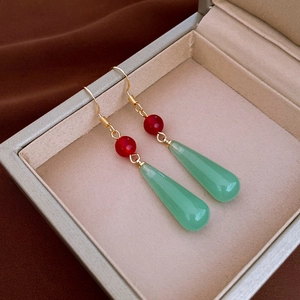 Close-up of green resin teardrop earrings with gold hooks in an elegant jewelry box
