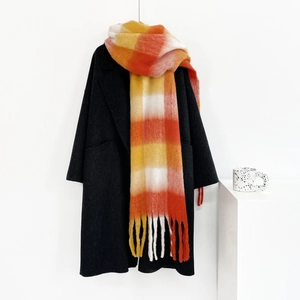 Detail of colorful plaid mohair scarf with tassels paired with a black wool coat