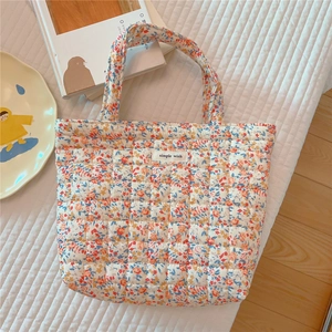 Detailed close-up of quilted floral hand tote with simple wish label on soft fabric