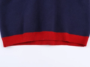 Détail d'un pull en maille bleu marine avec ourlet côtelé rouge et mailles lisses