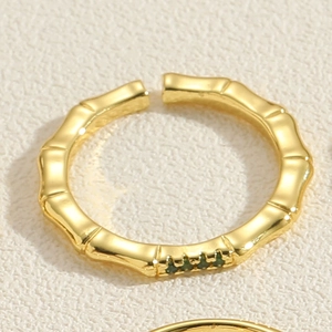 Nahaufnahme des goldenen Bambus-Rings mit drei grünen Zirkonia-Steinen, offenes Design