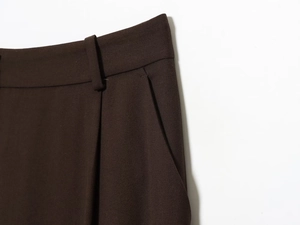 Detailed close-up of dark brown trousers featuring high waist loops and side slit pockets