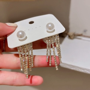 Detailed macro view of pearlescent studs with dangling crystal fringe tassel on a card