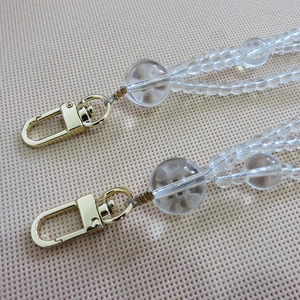Detail of transparent beaded bag chain with golden metal lobster clasps for handbags