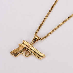 Detailed view of the golden pistol pendant necklace with textured finish and box chain