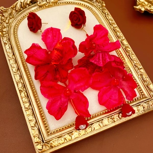 Détail de boucles d'oreilles fleurs rouges avec perles sur un plateau doré vintage