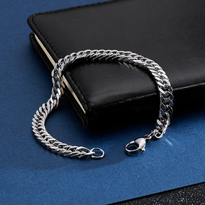 Nahaufnahme eines silbernen Panzerarmbands auf einem schwarzen Notizbuch