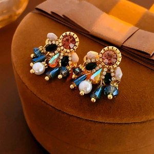 Macro shot of pink crystal and pearl drop earrings on a brown velvet jewelry box