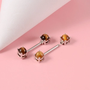 Macro detail of stainless steel nipple barbell featuring polished tiger eye stone beads