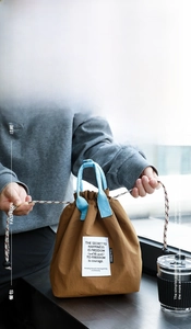 Detail view of thickened insulated brown lunch bag with drawstring closure and blue handles