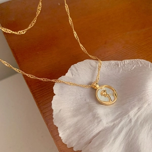 Macro shot of gold tulip necklace with white shell pendant on a natural seashell