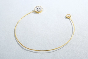 Detailed view of gold open cuff bracelet featuring two sparkling round cubic zirconia