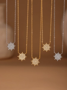 Detail view of gold and silver sunburst pendant necklaces with sparkling gemstones