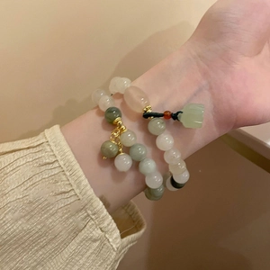 Detailed close-up of ethnic jade bead bracelets with lotus pendants on a woman wrist