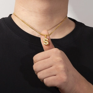 Gold-plated letter S pendant necklace with pearls on a black shirt background