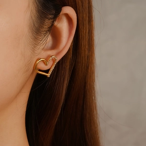Boucles d'oreilles cœur dorées 18 carats avec diamants portées par le modèle