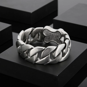 Detailed close-up of a silver Cuban link bracelet with a unique clover shaped metal clasp