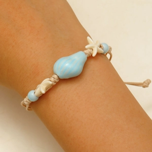 Close-up of handmade ocean bracelet with ceramic shell and starfish on beige cord