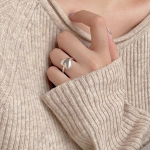 Polished 925 sterling silver heart-shaped ring styled with a beige knit sweater