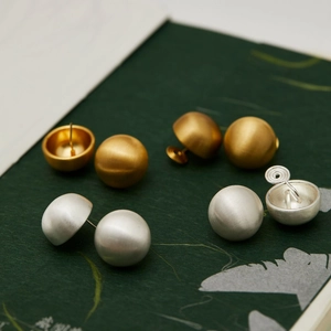Detail showing gold and silver brushed metal ball earrings on vintage green background