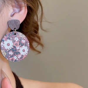 Gros plan de boucles d'oreilles pendantes rondes à fleurs avec détails en bois vintage