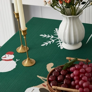 Detailed view of dark green Christmas tablecloth with white snowflake and snowman prints