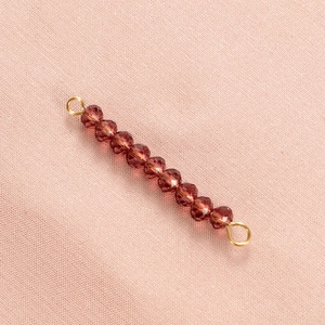 Detailed view of faceted brown crystal bead connector with golden metal loops