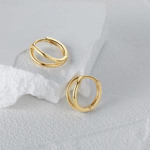 Detail of minimalist double-layered golden hoop earrings on white stone base