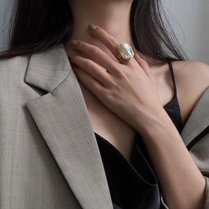 Detailed shot of an irregular baroque pearl ring with gold-plated metal on a model's finger