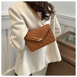 Brown quilted leather chain shoulder bag shown being worn on a model in a stylish setting