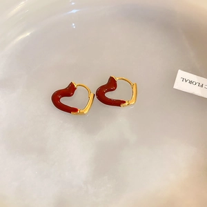 Macro view of dark red enamel heart charms on vintage golden hoop earrings