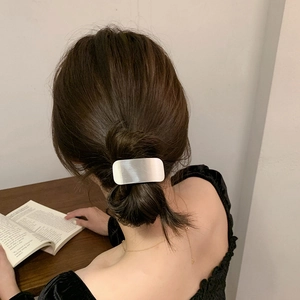 Minimalist silver rectangular metal hair clip worn on a bun hair style for daily look