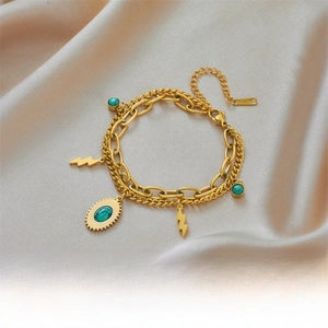 Detail of double-layer gold chain bracelet with lightning charms and turquoise stones