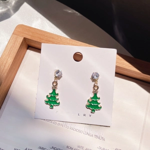 Detailed view of green enamel Christmas tree earrings with crystals on a jewelry card