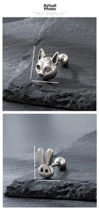 Detailed view of skull-snake and rabbit cartilage studs on dark slate stone